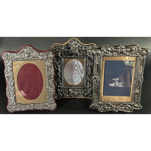 1179 - A silver photo frame with a floral embossed frame, 14 cm x 9.5 cm opening, together with two silver ... 