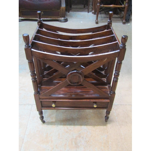 2213 - A mahogany x framed canterbury, with single drawer to base, over turned supports and brass casters, ... 