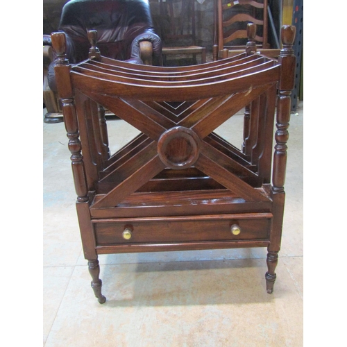 2213 - A mahogany x framed canterbury, with single drawer to base, over turned supports and brass casters, ... 