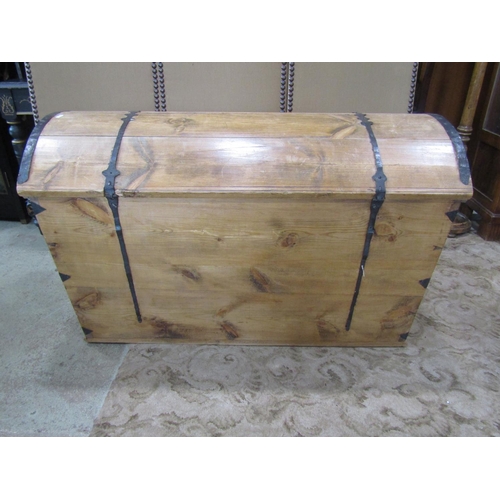 2217 - A large pale pine domed top trunk, with banded hinges over a locking cover (with key) flanked by car... 