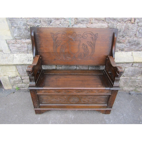 2288 - An Edwardian oak monks bench, with shallow carved detail and arms in the form of lions.