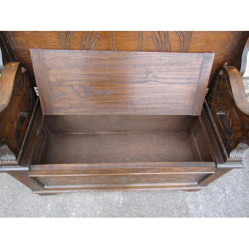 2288 - An Edwardian oak monks bench, with shallow carved detail and arms in the form of lions.