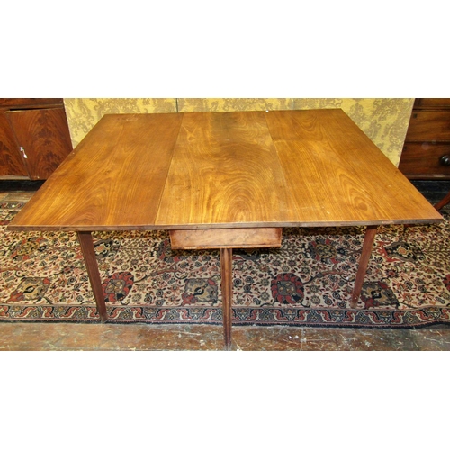 2667 - A Georgian mahogany drop leaf dining table raised on six square cut and tapering supports, the top a... 