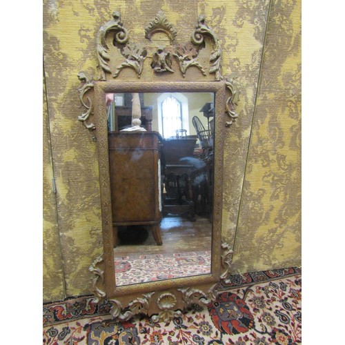 2744 - An antique gilded pier glass, with shaped outline and floral scrolling detail, 110cm high x 55cm wid... 