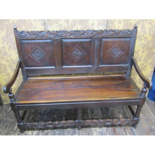 2743 - A Georgian oak settle the raised back incorporating three fielded panels with Tudor Rose and other d... 