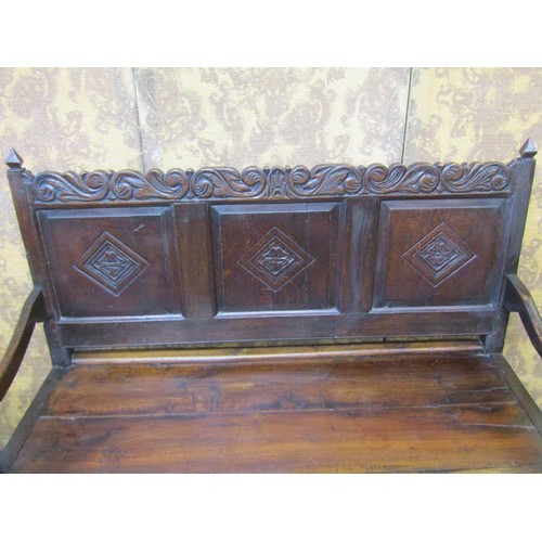 2743 - A Georgian oak settle the raised back incorporating three fielded panels with Tudor Rose and other d... 