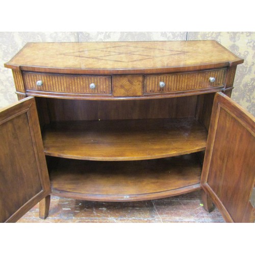 2660 - A reproduction walnut bow-fronted cabinet, the front elevation enclosed by two doors with brass gril... 