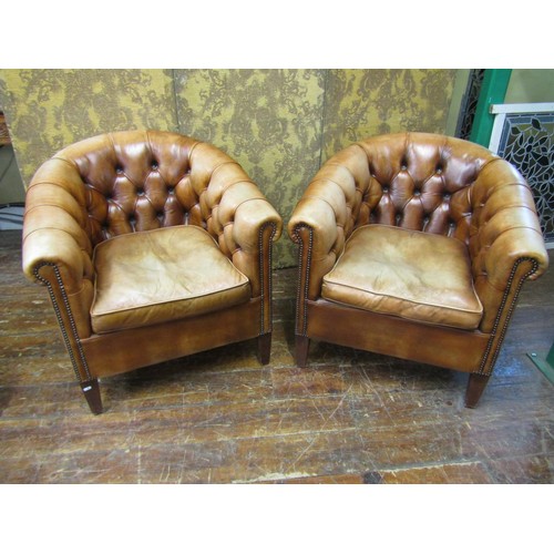 2650 - A pair of buttoned tan leather upholstered tub chairs, with brass stud detail, raised on square tape... 