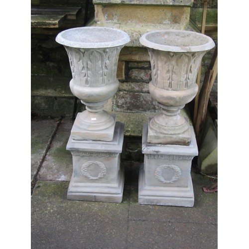 2021 - A pair of cast composition stone classical style garden urns with flared rims and repeating leaf rel... 