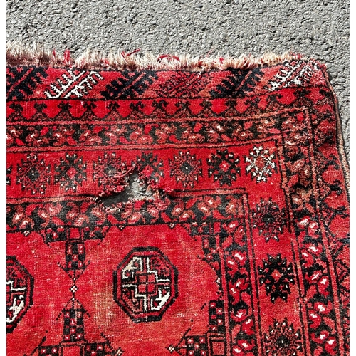 1774 - A Bokhara rug with two rows of small elephant foot guls on a faded pink ground, (as found one hole) ... 