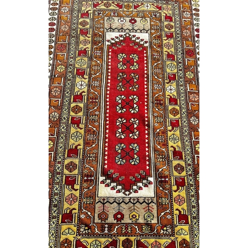 1778 - A Persian rug with a central rectangular panel and stylised flowers, 210 x 118cm approx