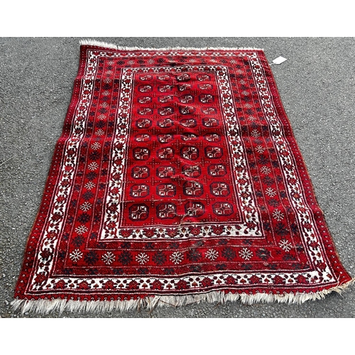 1785 - A small Afghan style red ground rug with a panel of four rows of guls on a red ground, worn in place... 