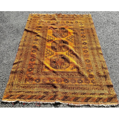 1788 - An Afghan carpet with a central row of elephant foot gul on a burnt orange ground 180 x 135cm approx