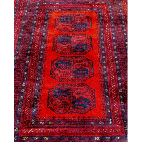 1805 - A Turkoman design carpet with four central connected medallions in tones of blue and orange, 190 x 1... 