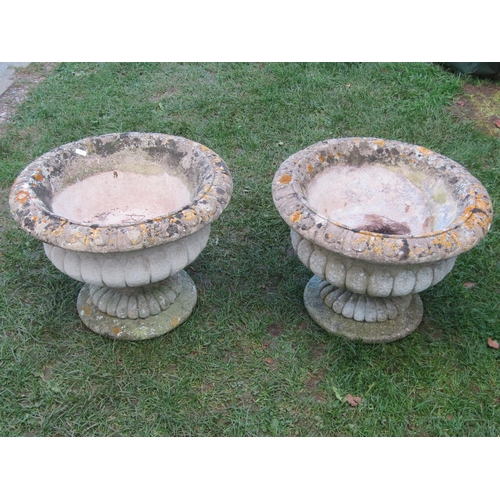 2090 - A pair of weathered composition stone circular lobbed garden urns raised on loose socles, 50 cm diam... 