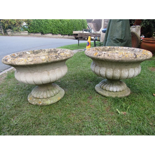 2090 - A pair of weathered composition stone circular lobbed garden urns raised on loose socles, 50 cm diam... 