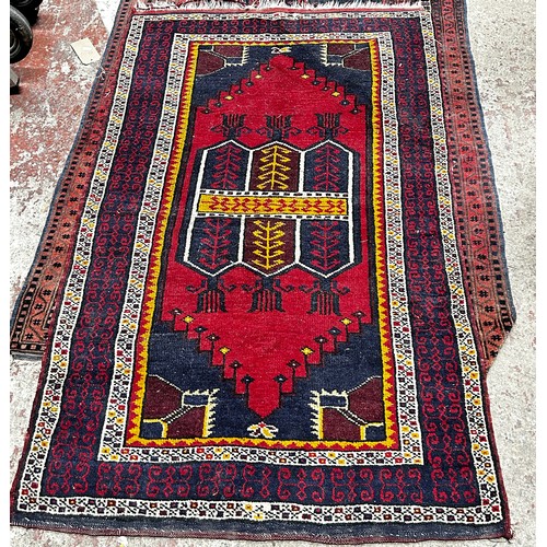 1797 - A Kazak style carpet with a central repeating rhombic pattern with a red panel and geometric borders... 