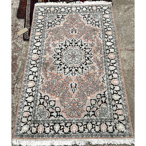 1803 - A Persian design rug with a central floral medallion on a pale pink floral ground, 158cm x 95cm appr... 