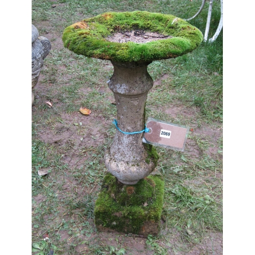 2069 - A weathered composition stone bird bath of circular form raised on a fixed baluster shaped pedestal ... 