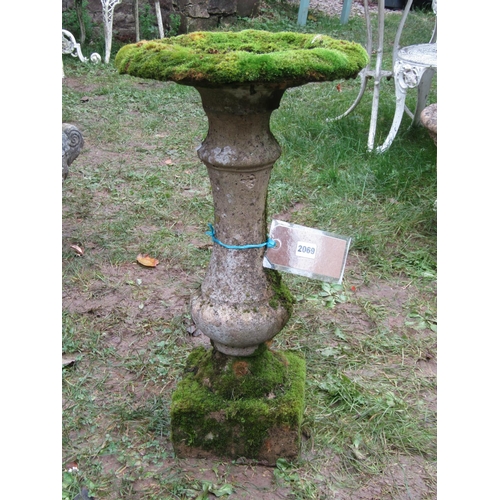 2069 - A weathered composition stone bird bath of circular form raised on a fixed baluster shaped pedestal ... 