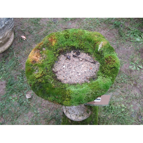 2069 - A weathered composition stone bird bath of circular form raised on a fixed baluster shaped pedestal ... 