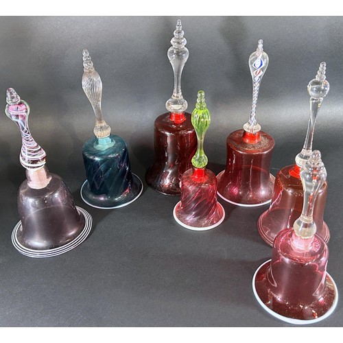 1131A - Seven Victorian Nailsea glass hand bells, 5 in a Cranberry colourway, including two with cotton twis... 