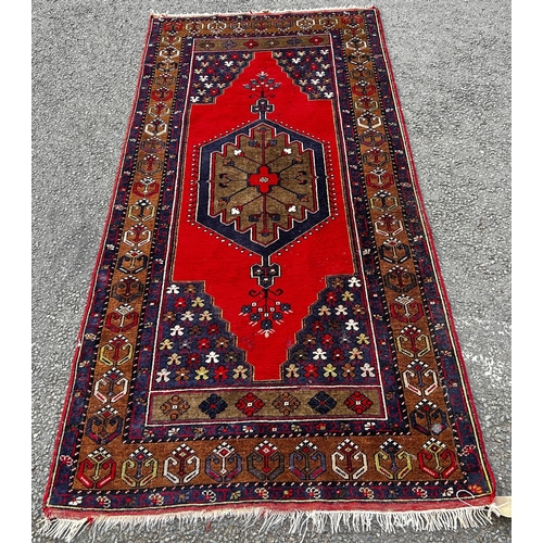 1823 - An Azerbaijan rug with a central medallion on a red ground, 210 x 107cm approx.