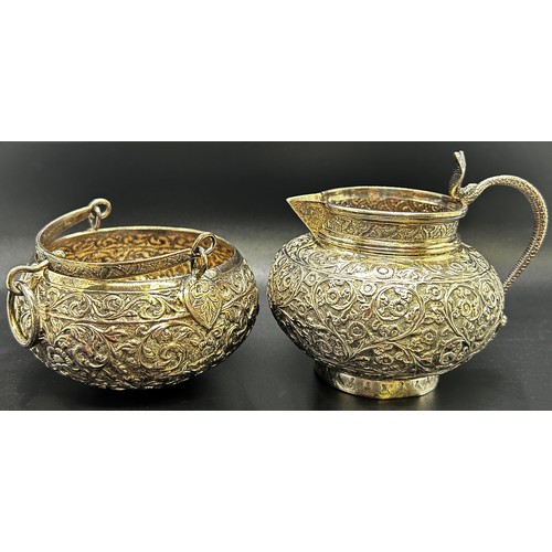 1240 - A three piece Indian silver metal tea service, heavily incised and engraved with an all over floral ... 