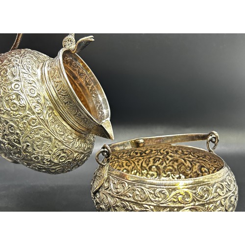 1240 - A three piece Indian silver metal tea service, heavily incised and engraved with an all over floral ... 