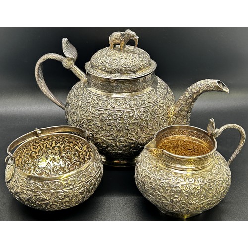 1240 - A three piece Indian silver metal tea service, heavily incised and engraved with an all over floral ... 