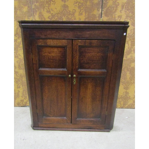 2218 - A Georgian oak hanging corner cupboard enclosed by a pair of moulded panelled doors, with two fixed ... 