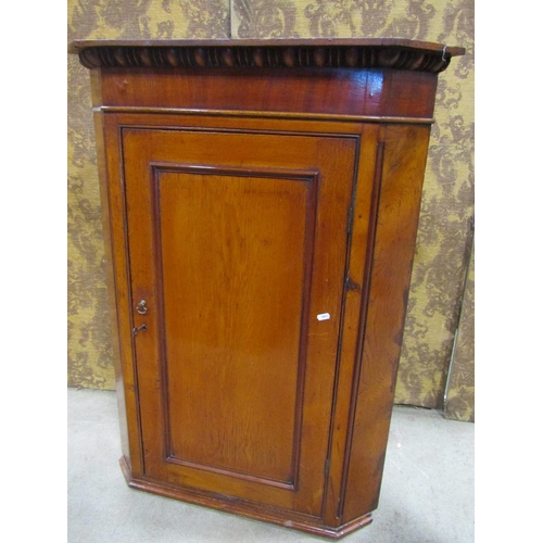 2188 - A Georgian pale oak and mahogany veneered hanging corner cupboard enclosed by a rectangular moulded ... 