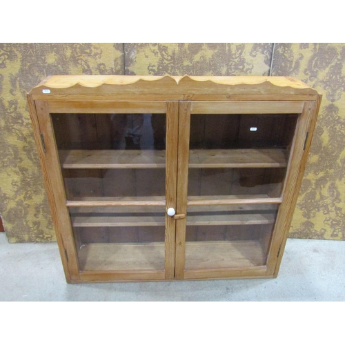 2228 - A stripped pine wall mounted kitchen cabinet enclosed by a pair of glazed and barred panelled doors,... 