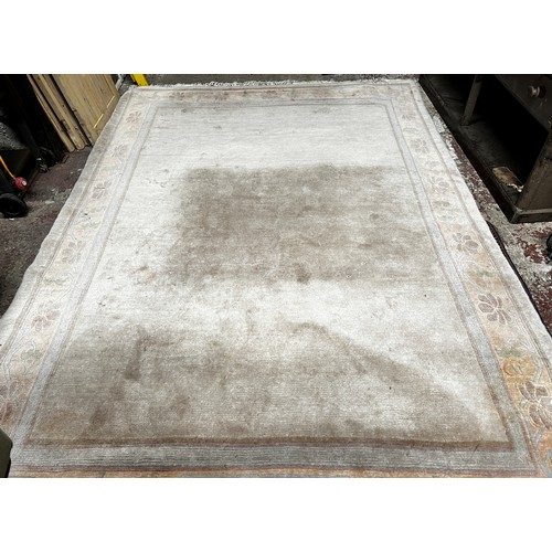 2723 - A large modern Chinese wool carpet in a pale pink with scrolling floral border, (stained in one corn... 