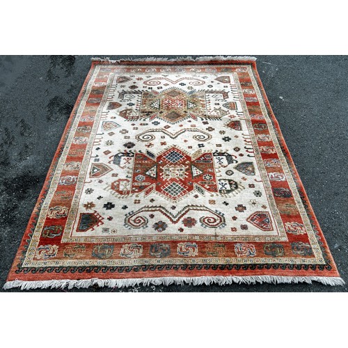 2732 - A Kazak type carpet, machine made, with an all over repeating pattern in pale hues on a cream field,... 