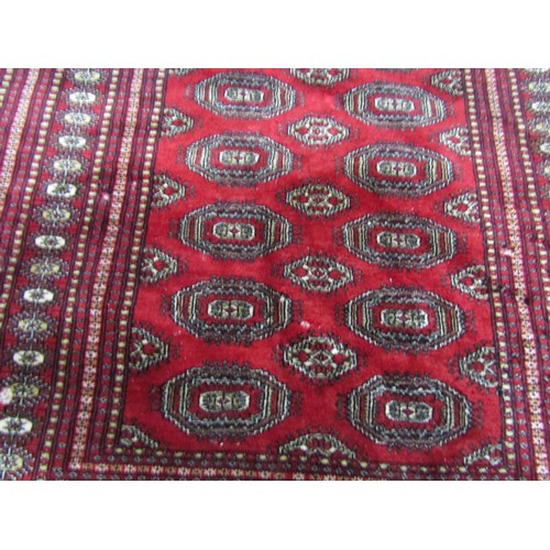 2722 - A Bokhara Carpet with alternating row of guls on a predominantly red ground, 180cm x 125cm.