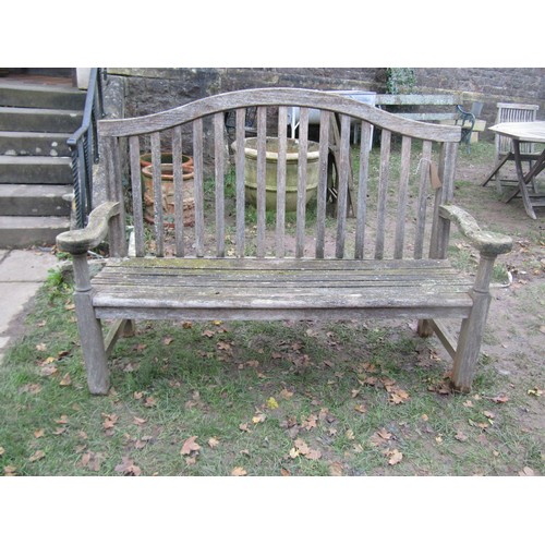 2075 - A weathered teakwood bench with slated seat and back beneath an arched rail, 159cm wide (af)