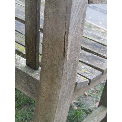 2075 - A weathered teakwood bench with slated seat and back beneath an arched rail, 159cm wide (af)