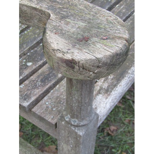 2075 - A weathered teakwood bench with slated seat and back beneath an arched rail, 159cm wide (af)