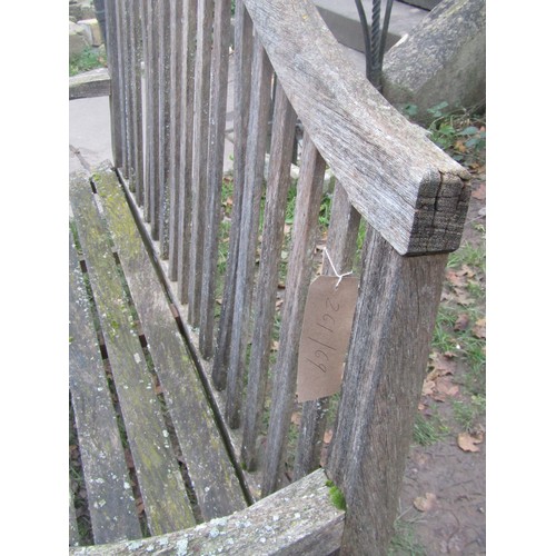 2075 - A weathered teakwood bench with slated seat and back beneath an arched rail, 159cm wide (af)