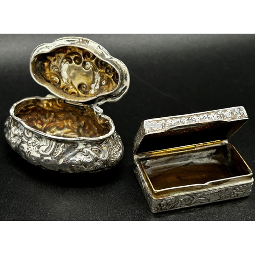 247 - A silver snuff box with classical muses to the lid, together with an oval shaped snuff box with scro... 