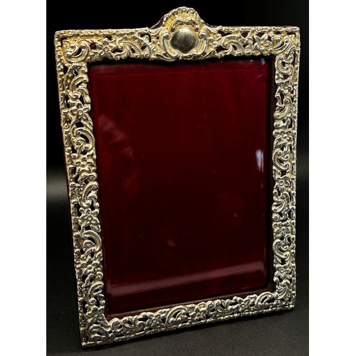 270 - A silver portrait photo frame with scrolling detail, red leather covered back stand, 10 x 14 cm open... 