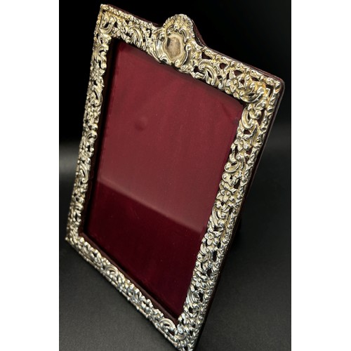 270 - A silver portrait photo frame with scrolling detail, red leather covered back stand, 10 x 14 cm open... 