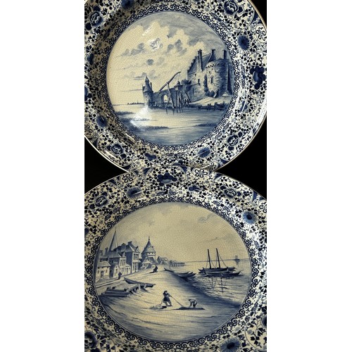 115 - Pair of Delft chargers, each with an individual hand painted landscape panel, set within repeating f... 