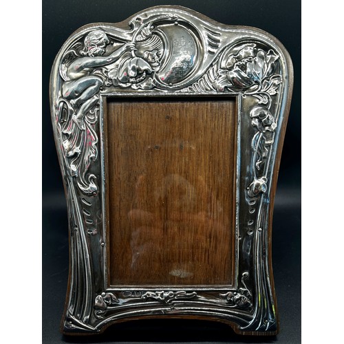 284 - An Art Nouveau silver photo frame with an angel and trailing flowers to the frame, bearing a horse r... 