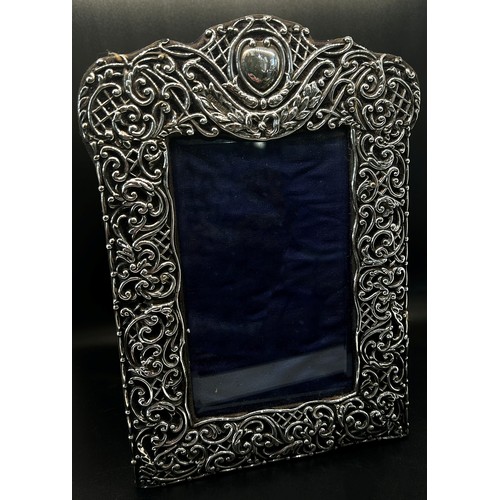 282 - An early 20th century photo frame with a heart shaped crest and extensive scrolling, 14 x 9.5 cm ope... 