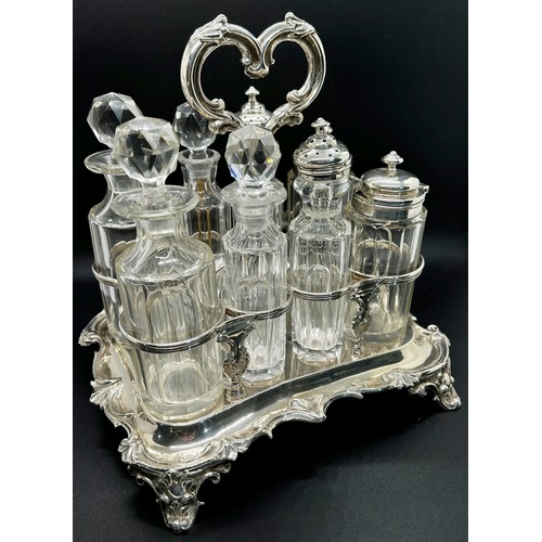 273 - A Victorian silver table condiment stand with eight glass bottles, the oblong scrolled stand is rais... 