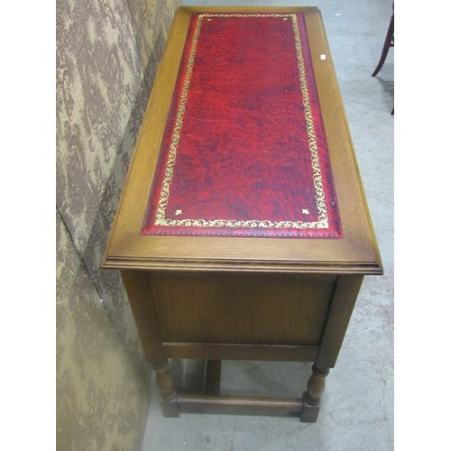 1208 - A reproduction pale oak writing table with inset red leather panelled top over an arrangement of fiv... 