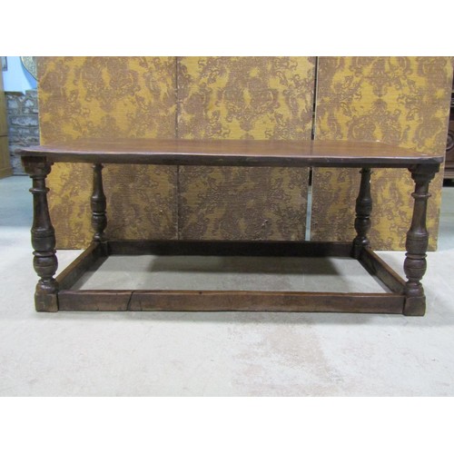 1249 - A low antique oak table of rectangular form with boarded top raised on turned block supports united ... 