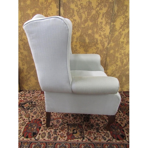 1436 - A wing chair in the Georgian style with shaped outline and supports, scrolled arms and cabriole fore... 